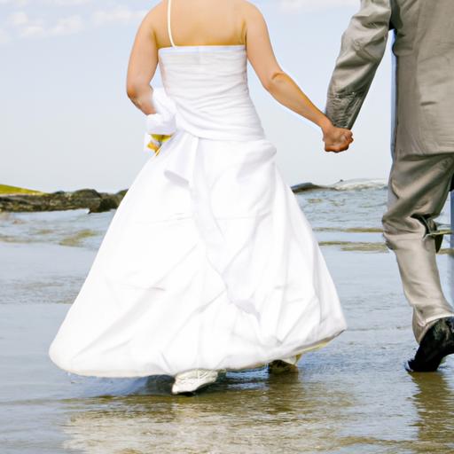 Đôi uyên ương tay trong tay đi bộ dọc bãi biển trong trang phục cưới